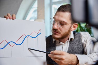 İş haritasına ve cep telefonuna işaret eden kalemle erkek ellerini kapat. Çizelgelerle çalışan insanlar. Borsa, iş adamı konsepti. Resepsiyonda bir iş. Çevrimiçi bağlantı ve iletişim