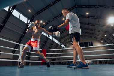 Boks antrenmanı. İki sporcu, profesyonel boksör ve kişisel antrenör spor salonunda boks yapıyor. Spor, güç, enerji ve güç. Motivasyon, başarı stratejisi, spor başarıları