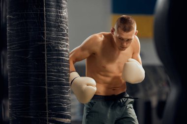 Kum torbası egzersizi. Spor salonunda boks antrenmanı yapan profesyonel erkek boksör. Dövüş sporları, strateji, eğitim, beceri ve başarılar. Sağlık, motivasyon