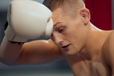 Boks ringinde sıkı çalıştıktan sonra dinlenme zamanı. Genç bir sporcu, spor salonunda spor yapmaya ara vermiş bir erkek boksör. Spor, beceri, güç kavramı.