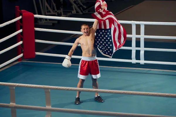 Winner emotions. Male boxer with american flag on his shoulders celebrating his victory. Strength, sport, facial expression and motion concept.