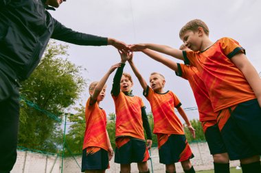 Kazanmaya kararlıyım. Küçükler futbol takımı maçtan önce dışarıda el sıkışıyor. Küçük çocuklar, siyah turuncu futbol takımı giymiş atletler. Spor, rekabet, takım çalışması ve başarılar kavramı