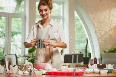 Genç güzel kız aşçılık uzmanı yemek pişirme üzerine video blogu yazıyor. Gülümseyen kadın video blogcusu ya da blog çekim muhabiri reklam videosu. Hobiler ve boş zaman aktiviteleri.