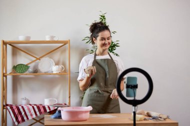 Çevrim içi atölye. Çekici, gülümseyen kız, ev stüdyosundaki malzeme kayıt videosuyla çömlek ustası. Hobiler ve boş zaman aktiviteleri. Uzaktan eğitim, online dersler, reklam
