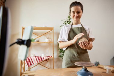 Çevrim içi atölye. Çekici, gülümseyen kız, ev stüdyosundaki malzeme kayıt videosuyla çömlek ustası. Hobiler ve boş zaman aktiviteleri. Uzaktan eğitim, online dersler, reklam