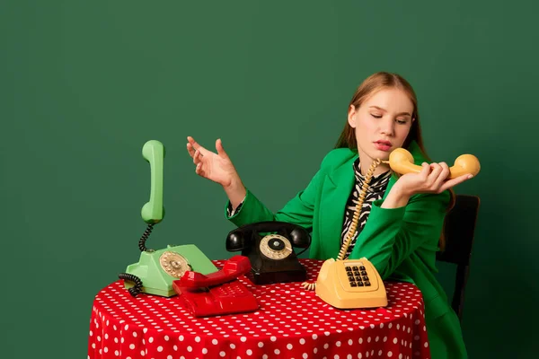 ポップアートの写真 レトロなオブジェや現代の若者 レトロスタイルの服を着た若い女の子がヴィンテージ電話でテーブルに座っています 補完的なトレンディーな色 ヴィンテージ レトロ80年代 70年代スタイル — ストック写真