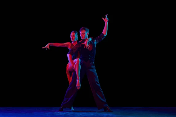 两个跳舞的人 穿着优雅的舞衣的舞女在运动 在霓虹灯的黑暗背景下表演 人类情感的概念 — 图库照片