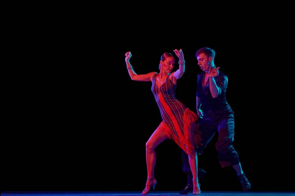 时尚的舞厅舞伴们穿着华丽的服装 在霓虹灯下 以性感的姿势在黑暗的背景下跳舞 人类情感的概念 — 图库照片