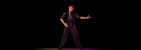 黒の衣装を着た一人の若い男 柔軟な男性ダンサーだけが暗い背景に孤立して立っています ダンスパートナーを待ってる 広告のチラシ 柔軟性 インスピレーションの概念 — ストック写真