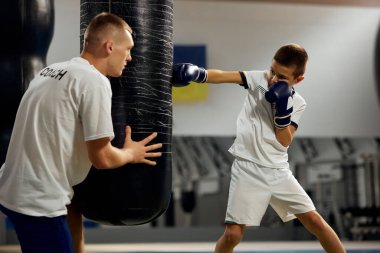 Okul çağındaki çocuk, boksör boksörü spor salonunda, kapalı alanda antrenman yapıyor. Öğrenim kavramı, zorluklar, spor, hobiler, rekabet. Spor kariyerinin başlangıcı, geleceğin şampiyonu.