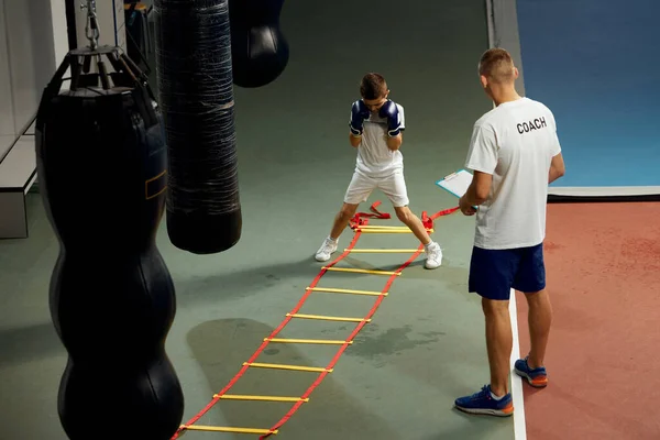 两个运动员 儿子和父亲正在拳击馆做运动 初学者的拳击运动与他的教练的拳击圈 精力和积极的生活方式 教孩子基本技巧的培训师 — 图库照片
