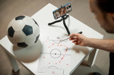 Çizimleri olan kağıt üzerinde futbol topu. Man Hands 'in son futbol maçının video kaydının üst görüntüsü ve oyunun stratejisi hakkındaki görüşlerini paylaşıyor. Spor, hobi ve eğlence konsepti.