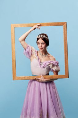 Resim çerçevesinden portre. Genç, zarif bir kadın, ortaçağ prensesi giyen bir aktris ya da mavi arka planda resim çerçevesi olan bir kontes elbisesi. Sanat kavramı, güzellik, ilham
