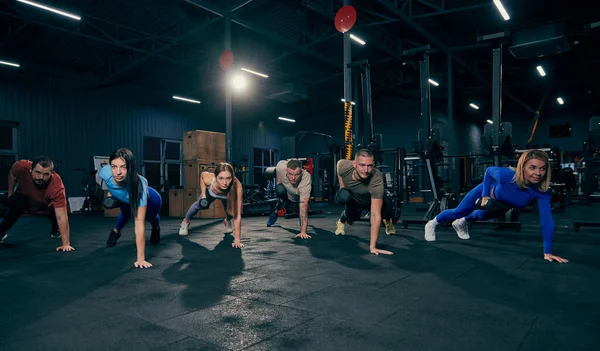 Group training. Sportive youth, muscled men and women in sports uniform workout at sport gym, indoors. Sport, active lifestyle, health, youth concept. Concept of health, sportive lifestyle, fitness