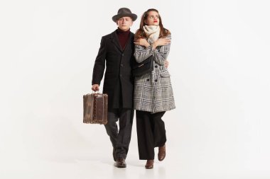 Sonbahar kıyafetleri içinde beyaz stüdyo arka planında yalnız yürüyen iki zarif çiftin tam boy fotoğrafı. Genç retro erkek ve kadın. Aile kavramı, aşk, bağbozumu, insanlar, yaşam tarzı, ilişki