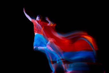 Hareket halindeki bir sporcu. Genç voleybol oyuncusu karanlık arka planda neon ışıkta izole edildi. Fitness, spor, takım, yarışma, şampiyonluk, profesyonel meslek. İlan için alanı kopyala