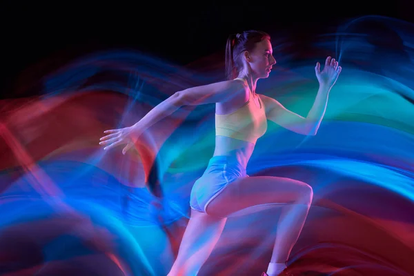 职业女运动员 在混合霓虹灯下在黑暗背景下跑步 穿着运动服的活泼姑娘在跑步或慢跑时练习 健康生活方式概念 — 图库照片