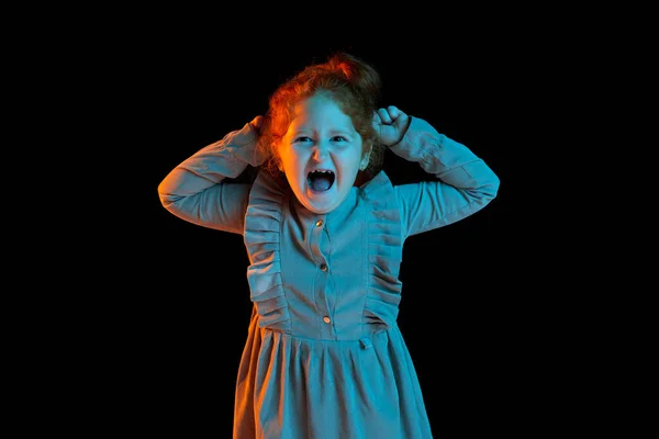 多愁善感的小女孩 穿着节日服装的迷人的孩子在霓虹灯下在漆黑的背景下独自高喊着 孩子的情绪 面部表情 看起来很生气很恼怒 — 图库照片