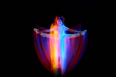 Mucize uçuşta. Beyaz elbiseli genç bir dansçı havada süzülüyor, karışık neon ışıkta karanlık arka planda hareket ediyor. Yaratıcı sanat, arzu, müzik, moda, dans. İlan için alanı kopyala