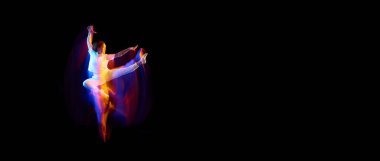 Yaratıcı dinamik atlet portresi, beyaz spor kıyafetleri içinde atlayan dansçı, karışık neon ışıkta karanlık arka planda uçan, ışıldayan. Sanat, arzu, müzik, moda. İlan için alanı kopyala