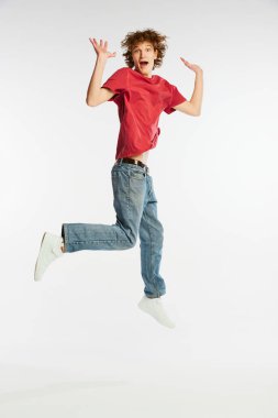 Heyecanlı genç adamın uzun bir portresi atlıyor, dans ediyor, beyaz arka planda izole edilmiş eğleniyor. Spor, dans, spor, mutluluk. Stüdyo çekimlerinde günlük kıyafetlerle modellik.