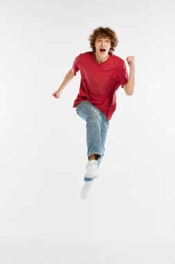 Beyaz arka planda yalnız koşan heyecanlı genç adamın ön kamera görüntüsü. Spor, dans, spor, mutluluk. Stüdyo çekimlerinde günlük kıyafetlerle modellik.