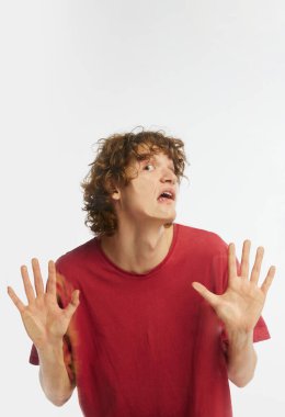 Genç yakışıklı bir adam, beyaz stüdyo arka planında şeffaf cama yaslanmış bir öğrenci. Yakın plan. İnsan duyguları kavramı, yüz ifadesi, reklam, moda, güzellik.