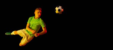 Gol! Genç futbolcu, hareketli futbolcu ve topla hareket eden aksiyoncu, neon ışıkta koyu arka planda izole edilmiş. Sanat anlayışı, yaratıcılık, spor, enerji. İlan, metin için boşluk kopyala