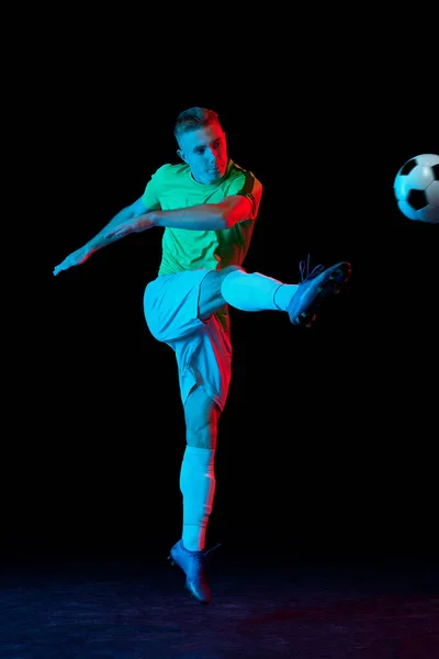 年轻的职业男足球员在运动中 在霓虹灯下被隔离在黑暗的背景下 体育概念 业余爱好 — 图库照片