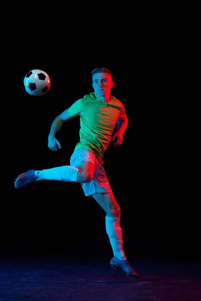 踢足球 在霓虹灯下 年轻活跃的足球运动员在黑暗背景下被隔离的动态镜头 体育概念 业余爱好 — 图库照片