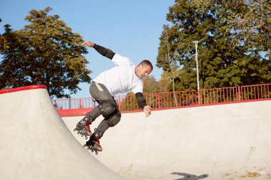 Modern paten parkında patenli enerjik bir adam hareket halinde. Profesyonel patenci tehlikeli ve cüretkar numaralar yapıyor. Spor, sağlık, hız ve enerji kavramı. Boş zaman.