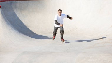 Hız, enerji ve güç. Bir adam, erkek patenci modern paten parkında paten eğitimi alıyor, açık havada. Hareket, hareket, beceri ve zorluklar. Farklı numaralar yapıyor. Amatör sporlar