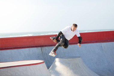 Modern paten parkında patenli enerjik bir adam hareket halinde. Profesyonel patenci tehlikeli ve cüretkar numaralar yapıyor. Spor, sağlık, hız ve enerji kavramı. Boş zaman.