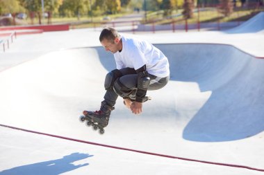 Modern paten parkında patenli enerjik bir adam hareket halinde. Profesyonel patenci tehlikeli ve cüretkar numaralar yapıyor. Spor, sağlık, hız ve enerji kavramı. Boş zaman.