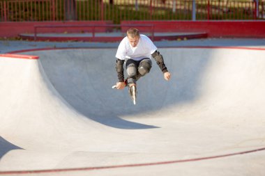 Hız, enerji ve güç. Bir adam, erkek patenci modern paten parkında paten eğitimi alıyor, açık havada. Hareket, hareket, beceri ve zorluklar. Farklı numaralar yapıyor. Amatör sporlar