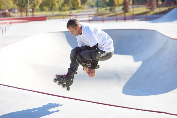 Energetic man on roller skates in motion at modern roller skate park. Professional roller skater doing dangerous and daring tricks. Concept of sport, health, speed, and energy. Leisure time