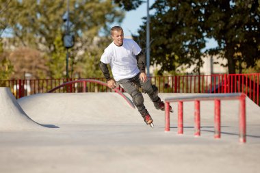 Modern paten parkında patenli enerjik bir adam hareket halinde. Profesyonel patenci tehlikeli ve cüretkar numaralar yapıyor. Spor, sağlık, hız ve enerji kavramı. Boş zaman.