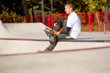 Hız, enerji ve güç. Bir adam, erkek patenci modern paten parkında paten eğitimi alıyor, açık havada. Hareket, hareket, beceri ve zorluklar. Farklı numaralar yapıyor. Amatör sporlar