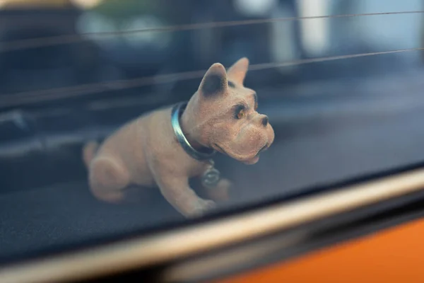 Köpek maskotu pencerenin arkasındaki eski bir arabanın rafında başını sallıyor.