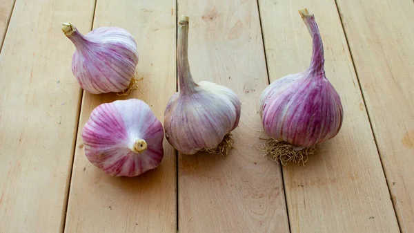 Quatre têtes d'ail mûr reposent sur un fond en bois. Épices et herbes. — Photo