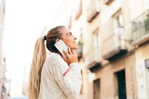金发女人在外面打电话 一个年轻的金发女人站在街上用手机拍的高质量照片 — 图库照片