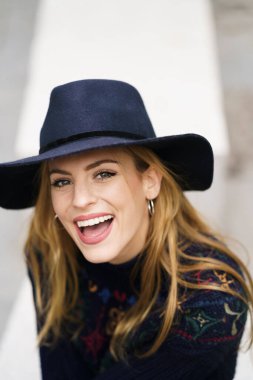 Lacivert şapkalı genç bir kadın gülümseyen kameraya bakıyor..