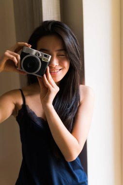 Pijama giymiş Çinli genç bir kadın eski model bir kamerayla poz veriyor.