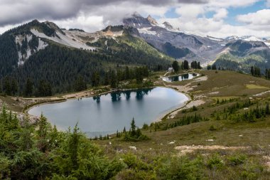Kanada, British Columbia 'daki Elf Gölü yürüyüşünün güzel manzarası. Dağlar ve buzullar gölü gözetliyor. Karamsar, bulutlu gökyüzü