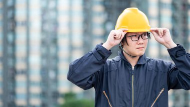 İnşaat alanında çalışan koruyucu giysili ve kasklı Asyalı tamirci. İnşaat mühendisliği, mimarlık, inşaat ve inşaat hizmeti kavramları.