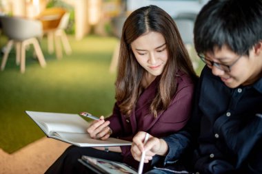 İş toplantısı ve ortaklık konsepti. Çekici Asyalı meslektaşlar iş yerindeki başlangıç projesi raporları hakkında konuşuyorlar. İş arkadaşları ofiste fikir alışverişinde bulunuyor..