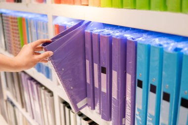 Erkek el kırtasiye renkli raf ekranından yeni mor halka bağlayıcı dosya klasörü seçimi. Ofis malzemeleri konsepti satın alma