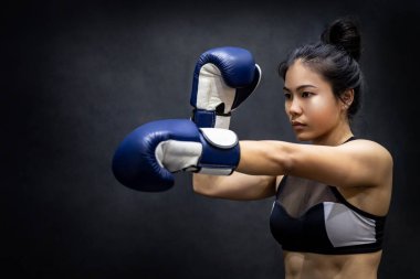 Genç Asyalı boksör kadın spor salonunda mavi boks eldivenleriyle aparkat pozu veriyor. Kadın boks sınıfı. Dövüş sanatları konsepti