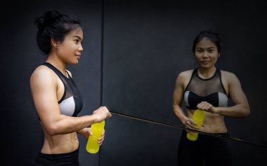 Genç Asyalı atlet kadın spor salonunda spor içeceği ya da spor sonrası enerji içeceği içiyor. Sağlıklı yaşam tarzı kavramı