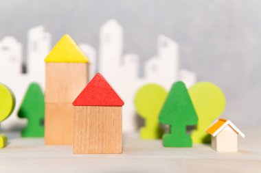 Masanın üzerinde bulanık şehir geçmişi olan tahta ev ve ağaç oyuncak bloğu modellerinden oluşan bir grup. Kentsel yaşam kavramı